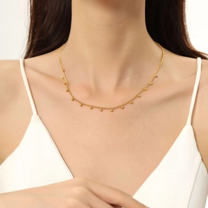 Dettaglio di un'elegante collana dorata con catena sottile e piccole perline pendenti