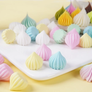 Colorful spiral drop-shaped miniature desserts in macaron tones on a white tray