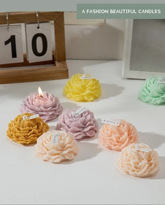 Vista dettagliata di candele profumate a forma di peonia con petali a strati e fiamma viva