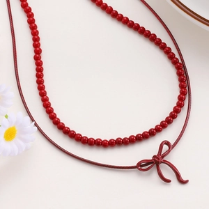 Close-up of double-layer red beaded necklace with a bow pendant and floral decor