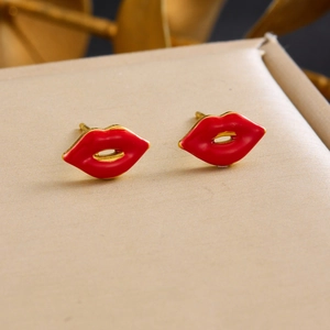 Boucles d'oreilles lèvres rouges plaquées or sur surface beige, détail parure bijoux