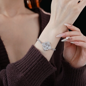 Vue macro d'un bracelet fleur argenté orné de zircons scintillants au poignet d'une femme