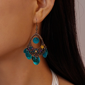 Bohemian bronze teardrop earrings with turquoise sequins shown on model ear