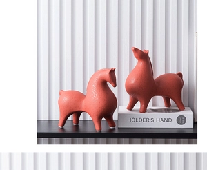 Gros plan de sculptures de chevaux en céramique minimalistes avec une finition orange texturée