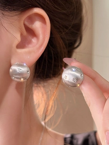 Close-up of brushed silver round stud earrings with sparkling star-shaped zircon inlays