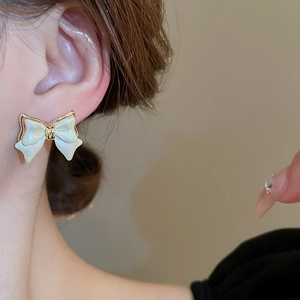 Close-up of model wearing pearl white bow earrings with elegant golden metal borders