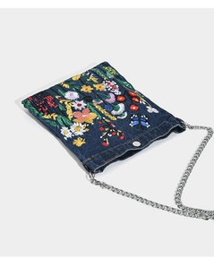 Close-up of vibrant floral embroidery and butterfly detail on blue denim crossbody bag