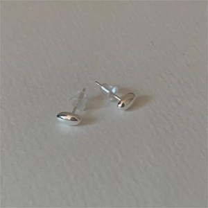 Detailed view of silver bean-shaped stud earrings with soft silicone backings