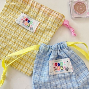 Detail of blue and yellow plaid drawstring storage bags with cute label and colorful cords