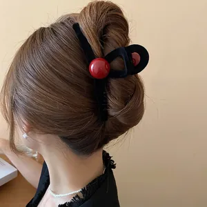 Minimalist black flocked hair claw clip with red beads worn on model back view