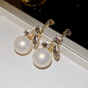 Detail of golden tassel earrings with faceted crystals and translucent white beads