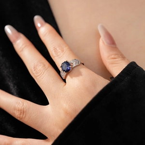 Gros plan d'une bague feuille en argent avec une pierre ovale bleue et des zircons