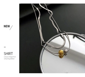 Detail of silver snake chain necklace featuring polished gold and silver ball pendants
