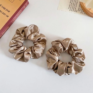 Flat lay of champagne faux silk scrunchies with elegant leopard and floral patterns