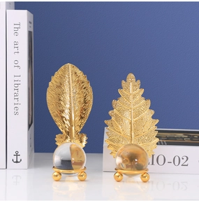 Detail of golden metal leaf sculptures holding transparent glass spheres on pedestals