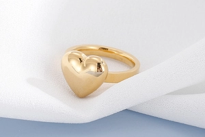Gros plan détaillé d'une bague en or polie en forme de cœur avec une finition miroir