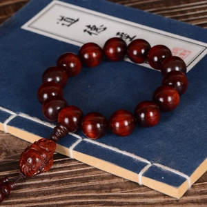 Polished lobular red sandalwood prayer beads with Maitreya Buddha pendant on blue book