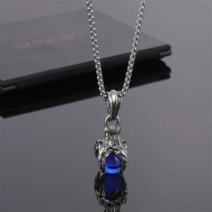 Détail du pendentif griffe de dragon argentée tenant une perle bleue sur chaîne box