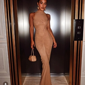 Détail d'une robe longue moulante beige à col montant avec sac à main assorti