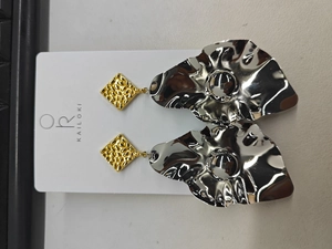 Close-up of mixed metal leaf earrings with gold square studs and wavy silver mirror drops