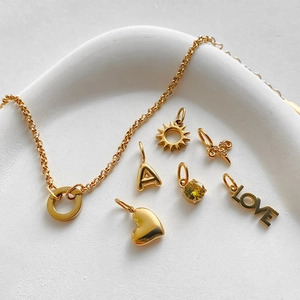 Detailed view of 14K gold plated stainless steel charms including heart and sun