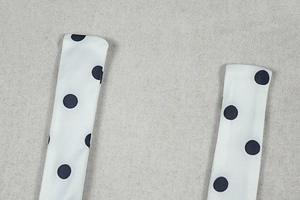 Detailed view of the polka dot shoulder straps and knotted halter tie on the dress