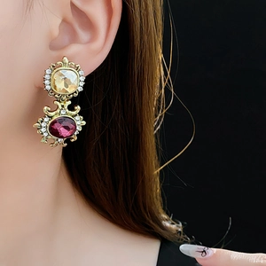 Close-up of vintage style gold earrings with yellow and purple gems worn by a model