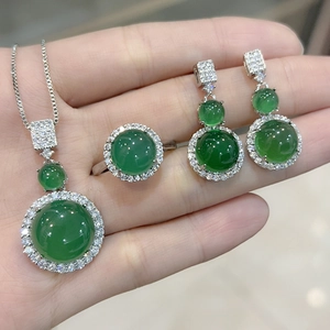 Detail of elegant silver jewelry set featuring round green chalcedony and crystal halo