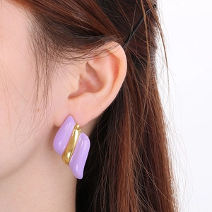 Gros plan d'un mannequin portant de grandes boucles d'oreilles rayées violet et or 18K