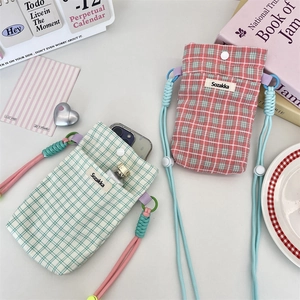 Top-down view of pink and green plaid fabric phone pouches with resin buttons on a desk