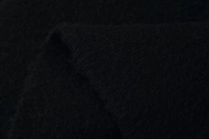 Close-up of high-quality black knit fabric showing soft texture and thick woven pattern
