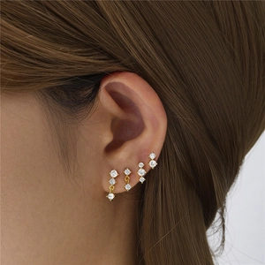 Detail of four-piece gold bow earring set with cubic zirconia on model's ear