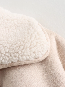 Macro detail of soft cream faux shearling lining and beige suede texture of the jacket