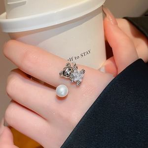 Detail of adjustable bear and pearl ring worn by hand holding a white ceramic coffee cup