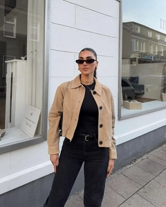 Détail d'une veste courte en daim marron avec de gros boutons noirs et col à revers