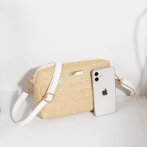 Minimalist straw crossbody bag with white straps shown with phone for size reference