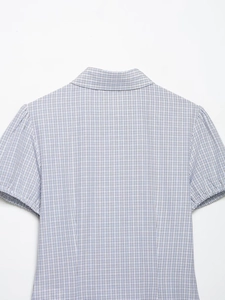 Detail showing the blue and white checkered pattern and sewing of the short sleeve shirt
