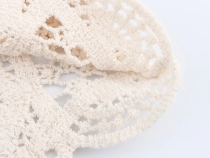 Close-up of intricate crochet knit pattern and soft cotton texture on beige summer top