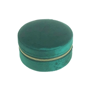 Detail of round dark green velvet jewelry box with metallic gold zipper closure