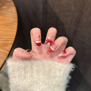 Christmas 3D bow press-on nails with red and pearl accents on cozy sweater background