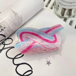 Detail of pink and blue marbled acrylic hair claw clip on aesthetic magazine background