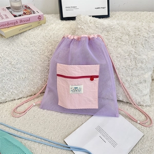 Détail d'un sac à dos en maille violette avec poche zippée rose et détails en perles