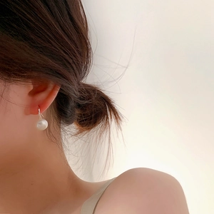 Close-up of minimalist S925 silver and natural freshwater pearl earrings on model