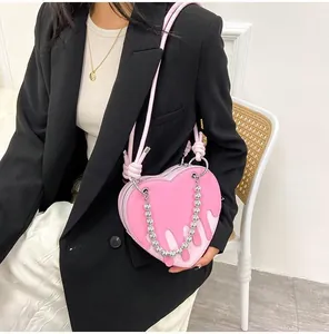 Detail of pink heart-shaped bag featuring silver metallic chain and liquid-drop design