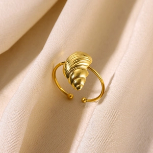 Detailed view of a gold shell-shaped open ring resting on elegant beige silk fabric