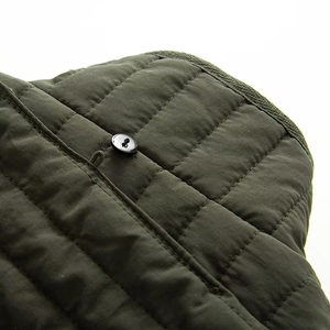 Detail of dark green quilted jacket featuring fine stitching and a black button closure