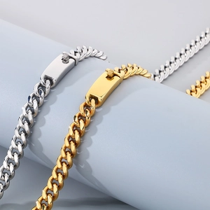 Detailed view of gold and silver cuban link bracelets with box clasps on blue pedestal