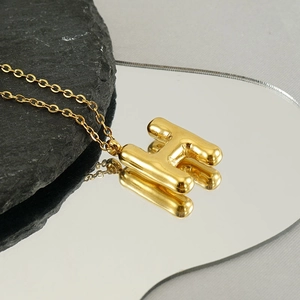 Macro view of a 3D bubble letter H pendant in gold plating with a mirror finish