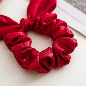 Close-up of red Christmas bow scrunchie featuring a premium glitter textured fabric finish