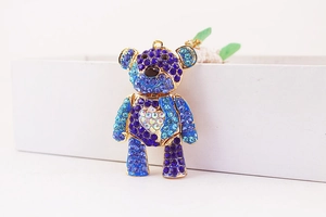 Macro shot of a golden bear charm embellished with gradient blue rhinestones